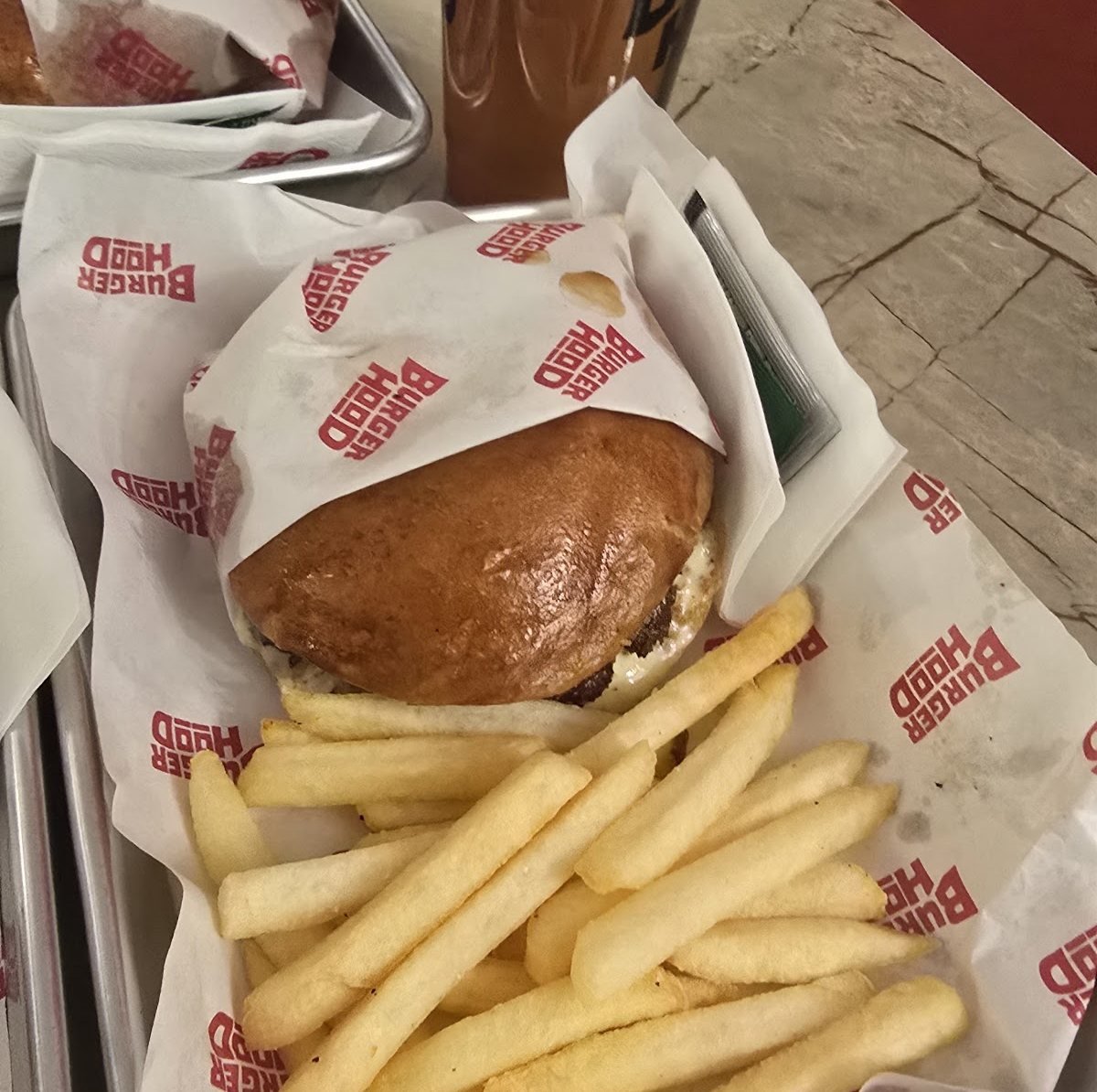 A Burgerhood burger and fries on a branded tray